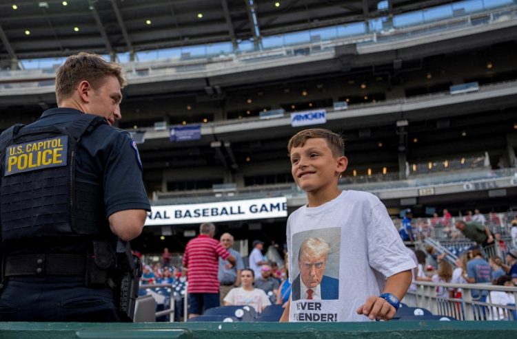 2024년 6월 12일 워싱턴 내셔널스 파크에서 열리는 연례 자선 의회 야구 경기장에서 한 소년이 트럼프의 머그샷이 프린트 된 티셔츠를 입고 있다. 로이터
